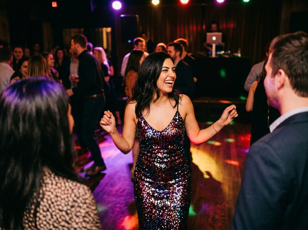 Mujer segura riendo y bailando en el centro de una pista de disco swinger con luces de colores